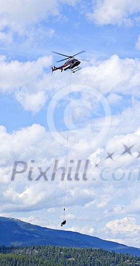 Rescue helicopter rescuing person by airlifting dangling on rope in Alberta Canada Rescue helicopter rescuing person by airlifting dangling on rope in Alberta Canada