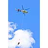 Rescue helicopter rescuing person by airlifting dangling on rope