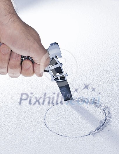 Handsaw cutting circular hole in ceiling tile Handsaw cutting circular hole in ceiling tile