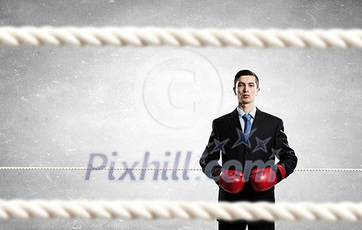Young businessman in red boxing gloves on cement background Young businessman in red boxing gloves on cement background