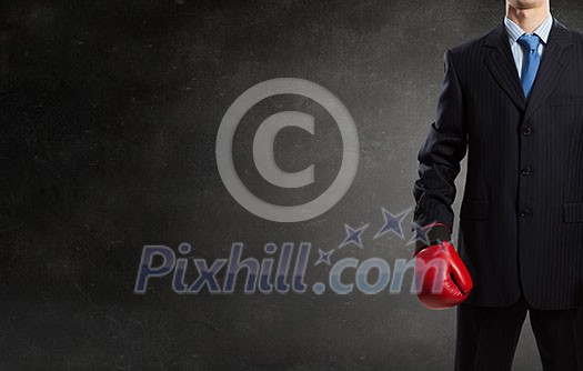 Young businessman in red boxing gloves on cement background