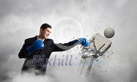 Young businessman in blue boxing gloves on cement background Young businessman in blue boxing gloves on cement background