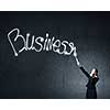 Businesswoman in darkness drawing business word with flashlight
