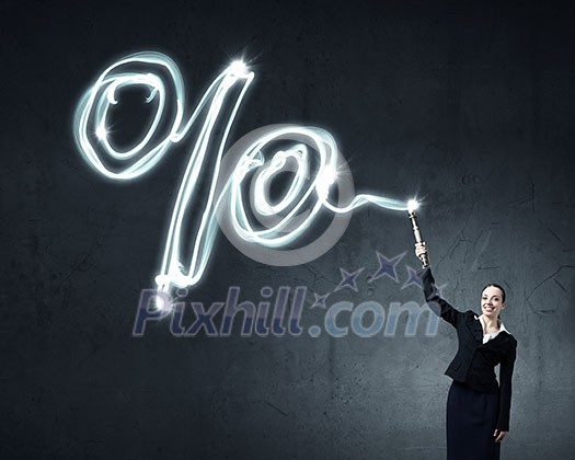 Businesswoman in darkness drawing percentage sign with flashlight
