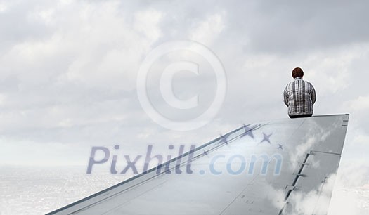 Middle aged stout woman sitting on edge of aairplane wing