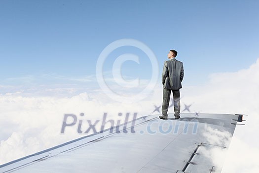 Young businessman standing on edge of airplane wing