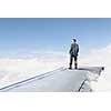 Young businessman standing on edge of airplane wing