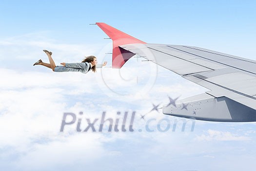 Young businesswoman flying on edge of airplane wing Young businesswoman flying on edge of airplane wing