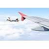Young businesswoman flying on edge of airplane wing