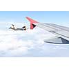 Young businesswoman flying on edge of airplane wing