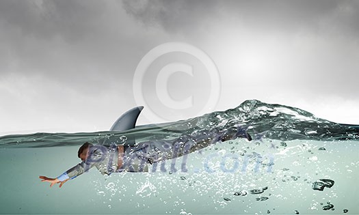 Young businessman with shark flipper swiming under water