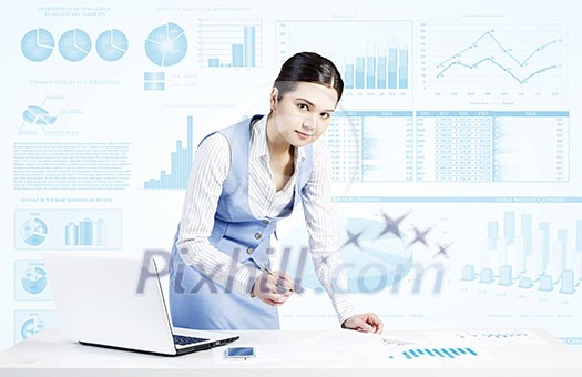 Businesswoman standing at table and writing with pen and infographs at background