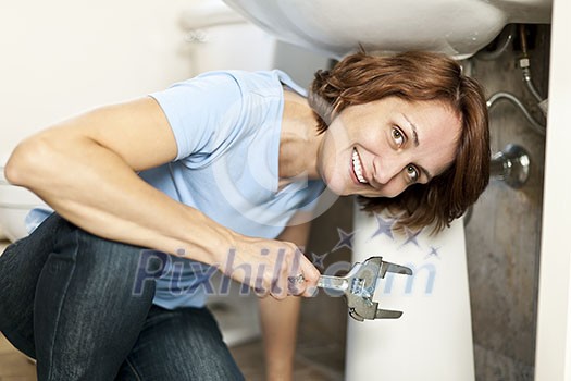 Confident woman repairing sink in bathroom at home Confident woman repairing sink in bathroom at home