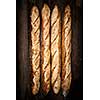 Four whole baguette bread loaves on dark wooden background