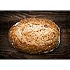 Artisan loaf of freshly baked multigrain bread on wooden background