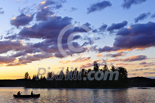 Silhouette of island and canoe on lake at sunset in Algonquin Park, Canada