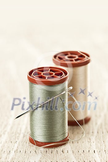 Two spools of thread with needle for sewing