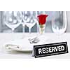 Reserved romantic restaurant table setting with roses plates and cutlery