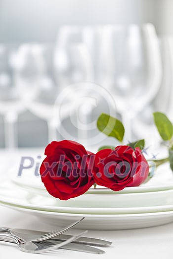 Romantic restaurant table setting for two with roses plates and cutlery