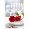 Romantic restaurant table setting for two with roses plates and cutlery