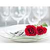 Romantic restaurant table setting for two with roses plates and cutlery