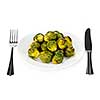 Plate of roasted green brussels sprouts with knife and fork isolated on white