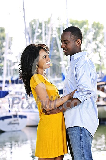 Young romantic couple facing each other hugging and standing at harbor