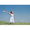 Young happy woman in green field with blue sky in background