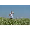 Young happy woman in green field with blue sky in background