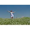 Young happy woman in green field with blue sky in background