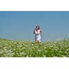 Young happy woman in green field with blue sky in background