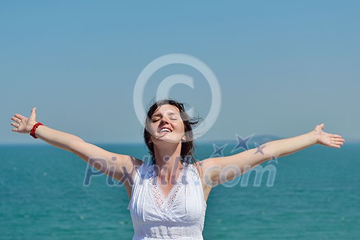 Happy  young woman with spreading arms, blue sky with clouds in background  - copyspace