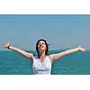 Happy  young woman with spreading arms, blue sky with clouds in background  - copyspace