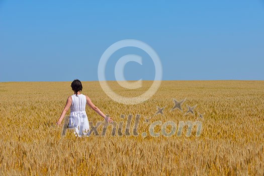 Young woman standing jumping and running on a wheat field with blue sky the background at summer day representing healthy life and agriculture concept Young woman standing jumping and running on a wheat field with blue sky the background at summer day representing healthy life and agriculture concept
