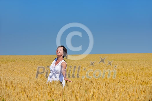 Young woman standing jumping and running  on a wheat field with blue sky the background at summer day representing healthy life and agriculture concept