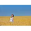 Young woman standing jumping and running  on a wheat field with blue sky the background at summer day representing healthy life and agriculture concept