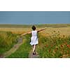 Young woman standing jumping and running  on a wheat field with blue sky in  background at summer day representing healthy life and agriculture concept