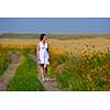 Young happy woman in green field with blue sky in background