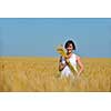 Young woman standing jumping and running  on a wheat field with blue sky the background at summer day representing healthy life and agriculture concept