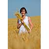 Young woman standing jumping and running  on a wheat field with blue sky the background at summer day representing healthy life and agriculture concept