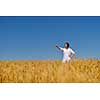 Young woman standing jumping and running  on a wheat field with blue sky the background at summer day representing healthy life and agriculture concept