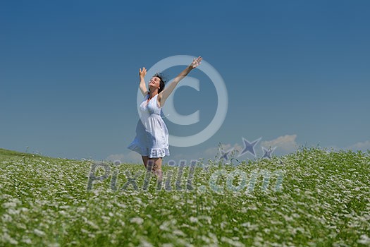 Young happy woman in green field with blue sky in background