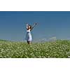 Young happy woman in green field with blue sky in background