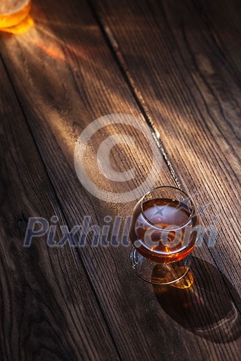 Cognac in glass on the wooden surface Cognac in glass on the wooden surface