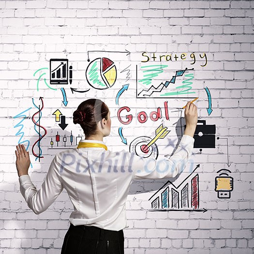 Businesswoman standing with back drawing business ideas on wall