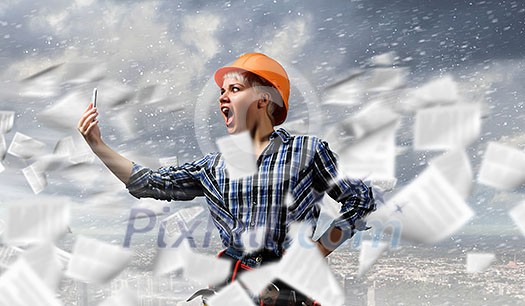 Young emotional woman mechanic screaming in mobile phone Young emotional woman mechanic screaming in mobile phone