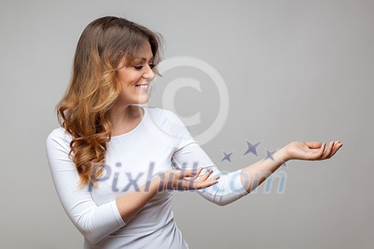 Attractive smiling woman show something on grey background Attractive smiling woman show something on grey background
