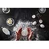 Woman's hands knead dough on table with flour and ingridients. Top view.