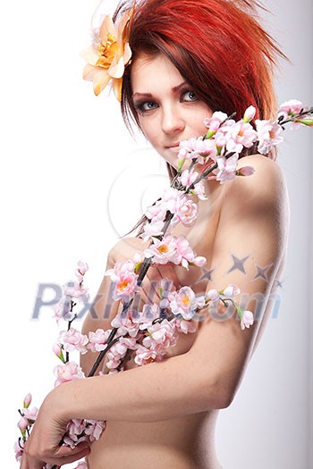 Portrait of beautiful naked woman with spring flower in hair on white