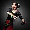 young woman dancing flamenco with castanets on black